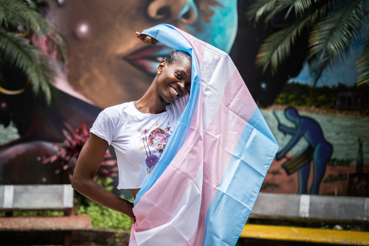 A trans woman holds the trans flag.