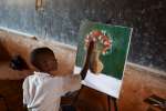 A young artist works on his still life of a vase of flowers.