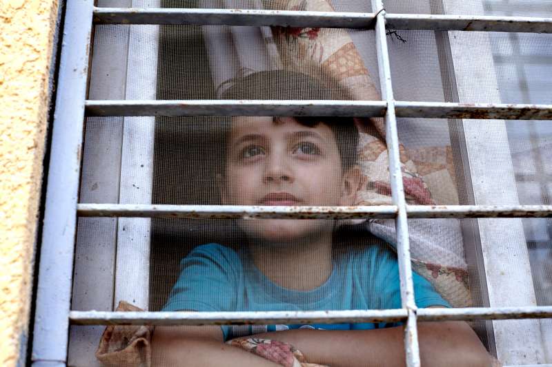Syrian refugee, Mahmoud, aged nine, looks out of the window of his family's rented apartment in 6th of October City, part of greater Cairo, Egypt. 