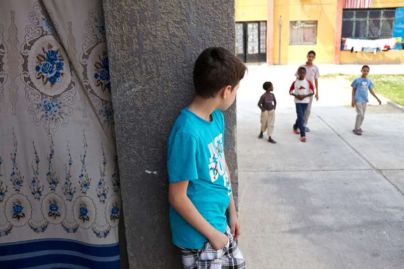 Mahmoud watches as a group of Egyptian children make their way past his home in the Beit Al Aila neighbourhood of 6th of October City, a satellite suburb of Cairo, Egypt. He became the target of bullies when public sentiment turned against Syrians.  