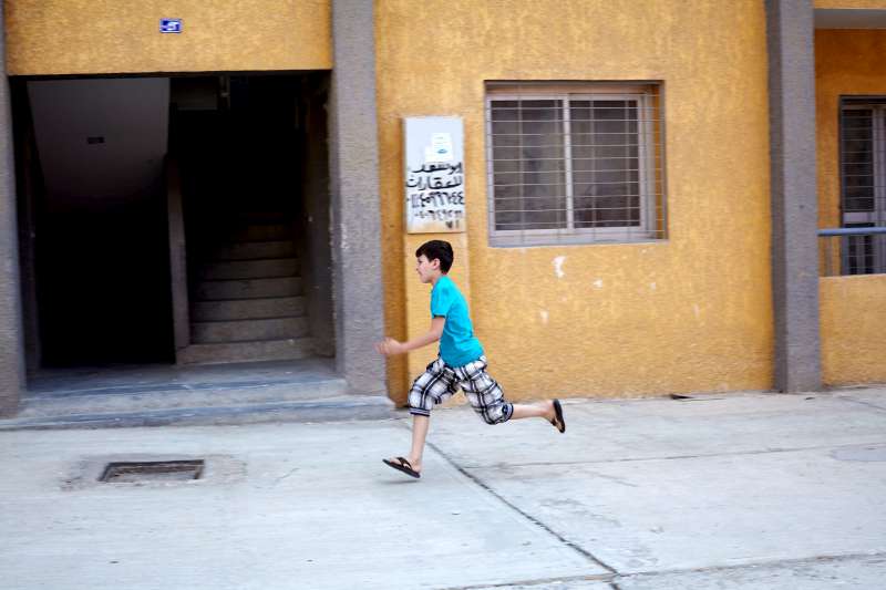 Mahmoud runs to visit a neighbor in the drab housing estate where his family's apartment was located. 