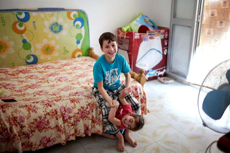 Mahmoud plays with his sister in their apartment in the Beit Al Aila neighbourhood. His father says that his son used to play with local children, but they turned against him.  