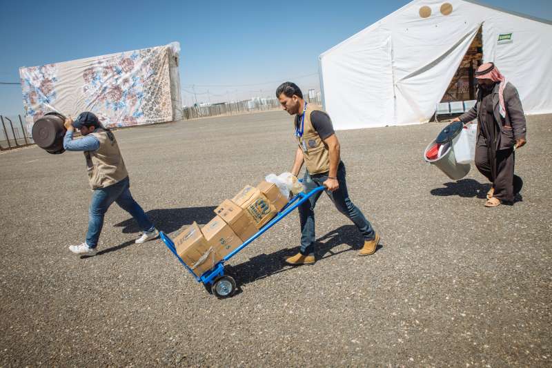 Staff from the French aid agency, ACTED, help Abu Saleh carry the food packages and other essential items that the family will need as they begin a new life at Azraq camp.
