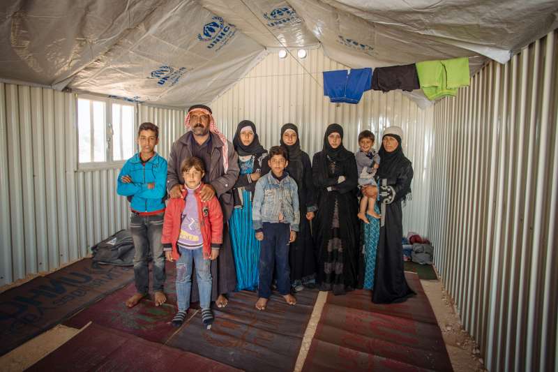 Abu Saleh, his wife, Dalah, and their seven children pose in their spartan new shelter. It will soon become more homely. It's a far cry from their home in northern Syria, but at least they are safe.
