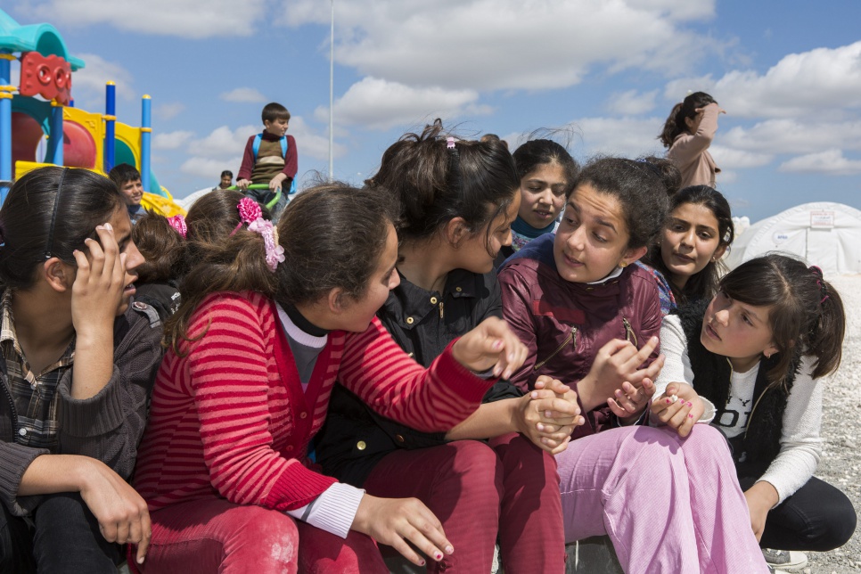 Ivra (wearing pink trousers) sits and talks with friends between classes outside a school in Suruç refugee camp in Turkey.
