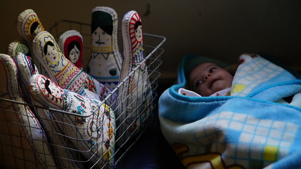A newborn baby sleeps next to Amina's embroidered dolls.