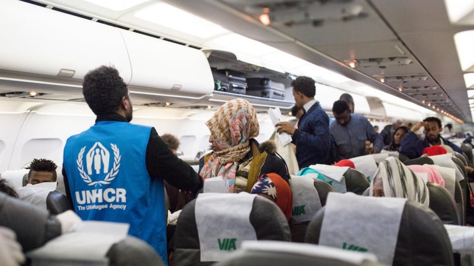 UNHCR staff assist vulnerable refugees as they leave the plane.