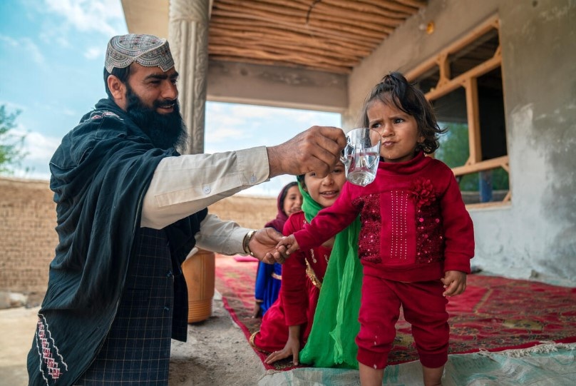 An Afghan man with his child in a permanent shelter