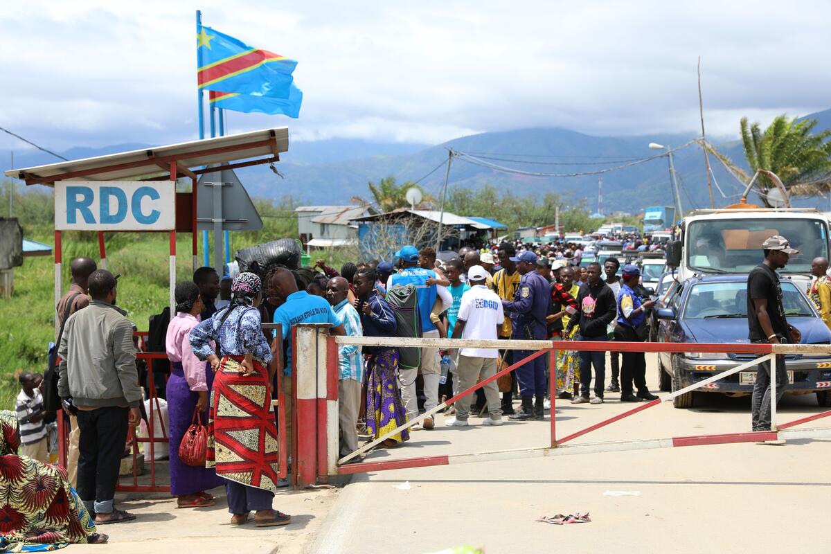 Many people and vehicles wait on the road by the border post on the Burundi-DRC border. Many people and vehicles wait on the road by the border post on the Burundi-DRC border.