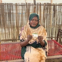 A refugee woman holds out her ID card in Sudan's White Nile state.