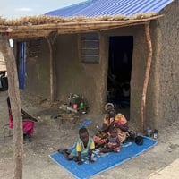 Nyagak Akuoch Akuei and her grandchildren sitting outside their home in Hai Matar, Malakal. The house and land, supported by UNHCR and the European Union, mark a new start after decades of displacement.