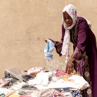 Halima sorting through new clothing items and everyday goods she sells in her shop that she opened after receiving a loan from a local Village Savings and Loans Association.