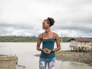 A trans woman stands on the banks of a river in Colombia's Chocó Department.