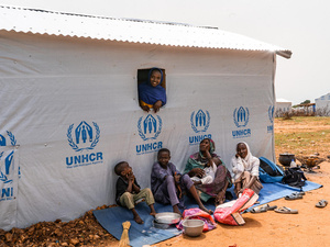 Ana Mahmoud Ousman, a refugee mother who fled the conflict in Sudan, seated with her children outside their new shelter at the Metché refugee settlement in Chad.