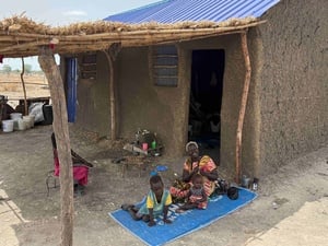 Nyagak Akuoch Akuei and her grandchildren sitting outside their home in Hai Matar, Malakal. The house and land, supported by UNHCR and the European Union, mark a new start after decades of displacement.