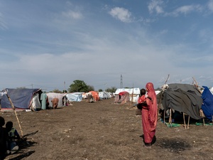 Fatima, displaced from her home in Kurmuk, holds her youngest child in the Al Karama gathering site in Damazine, Blue Nile State, Sudan.