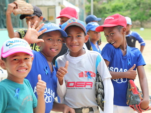 Four boys playing baseball and smiling at the camera