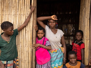 A woman and four children stand outside at a bamboo shelter