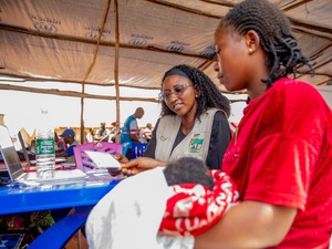 A woman siting in a UNHCR registration centre while holding her baby