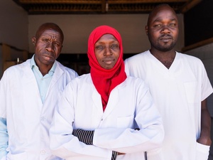 Three medical staff look at the camera, looking serious. 