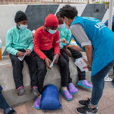 A UNHCR staff member shows her identification to three children