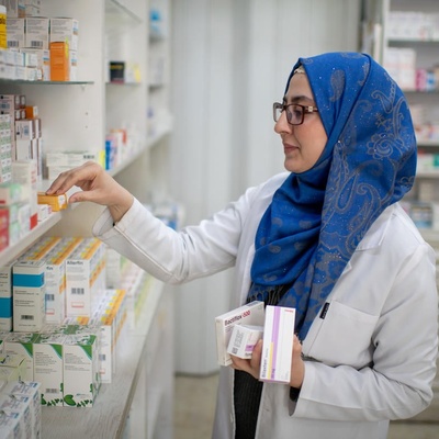 Une femme range des médicaments dans une pharmacie.