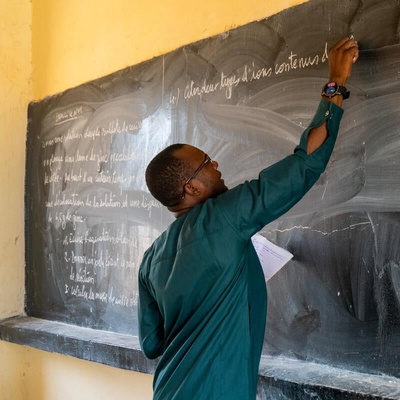 A man writes on a blackboard. 
