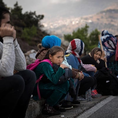 Des hommes, des femmes et des enfants attendent sur le bord de la route en Grèce.