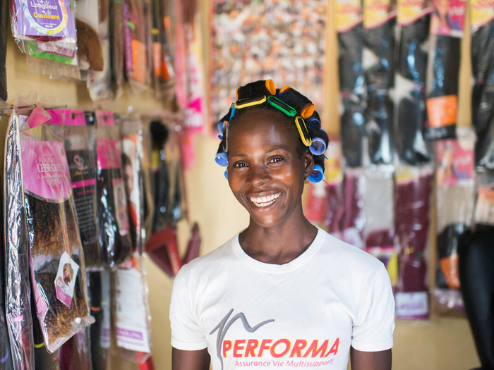 Elodie smiles for the camera inside her hair salon, she has curlers in her hair.