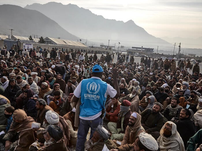 A UNHCR staff member assists displaced families waiting to receive winter cash assistance in Kabul.