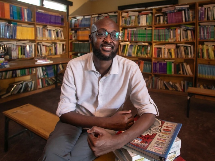 Abdullahi Mire souriant dans une bibliothèque
