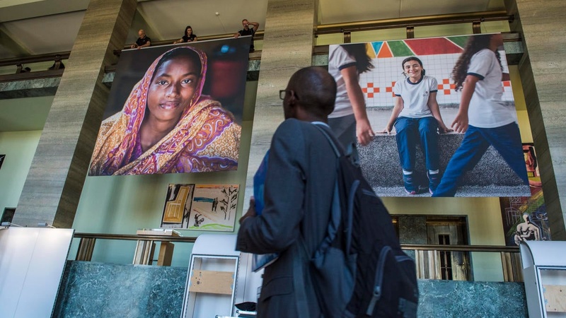 A person walks past a series of posters at the 2019 Global Refugee Forum. 