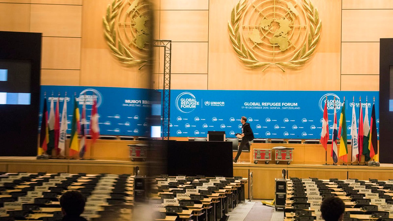 A conference room with a stage and rows of seats.