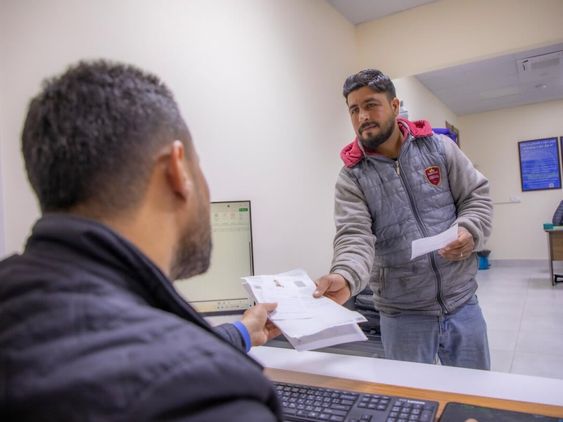 A Syrian refugee living in Iraq receives official documents from a UNHCR staff member.