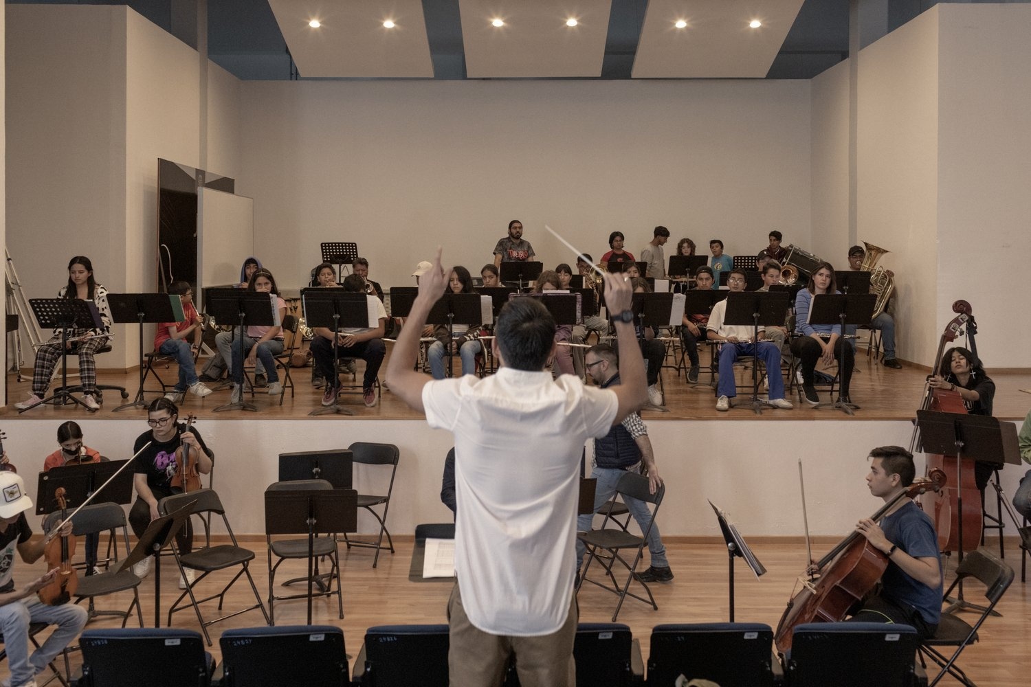 A man conducts an orchestra as they rehearse.