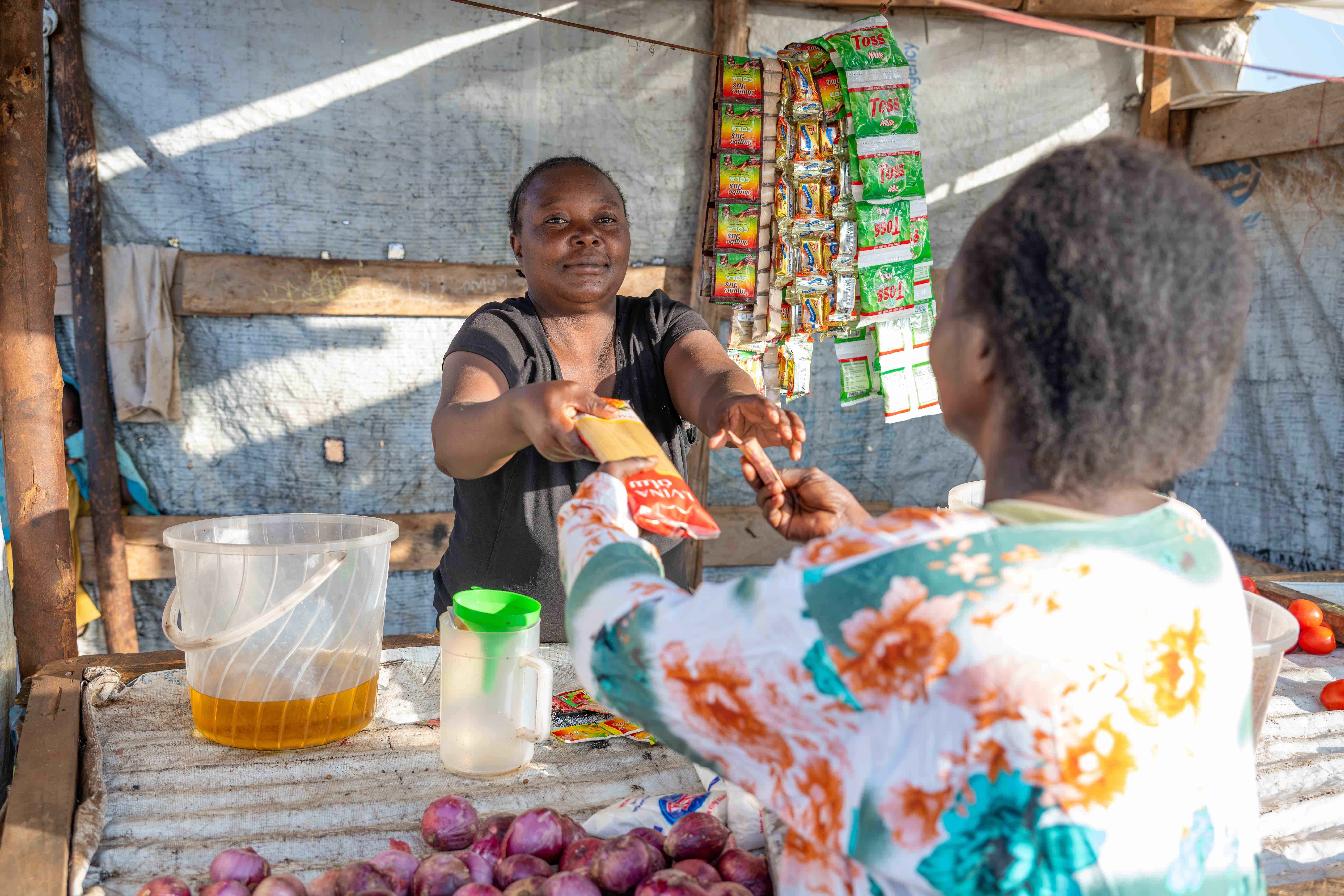 Bahati, a refugee from the Democratic Republic of Congo, serves a customer at her small shop in Kakuma.