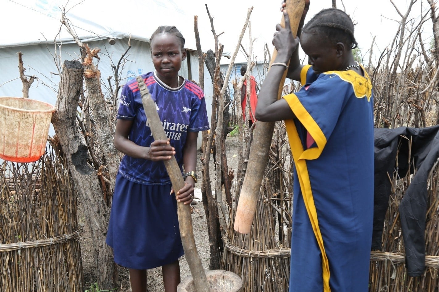 Nyahok, Joseph's wife, and their daughter Nyaruach prepare a meal outside their shelter. 