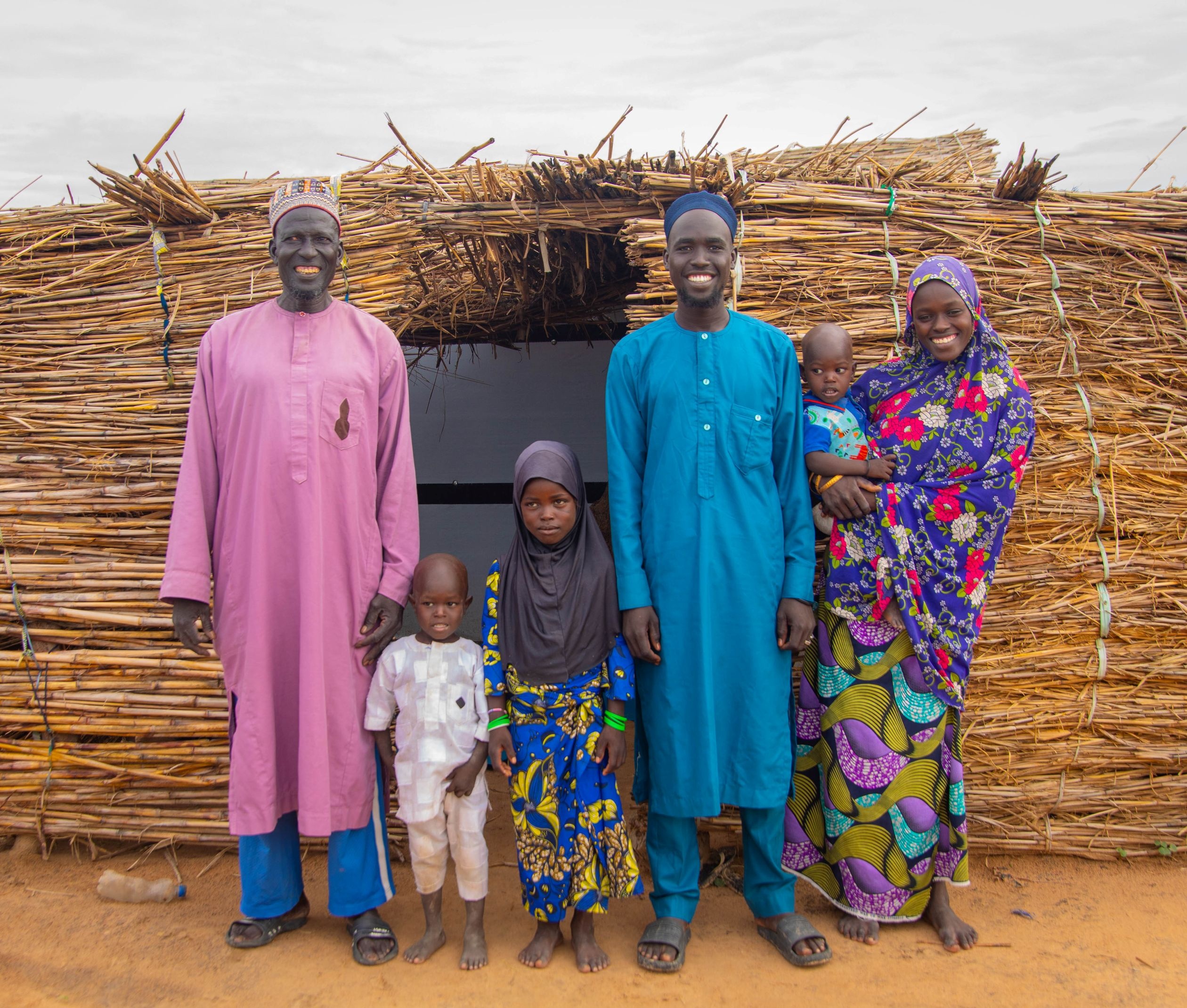 Boukarou Umati and family posing outside a temporary constructed shelter following their displacement due to conflict near the Border town of Kolofata, Far North region.