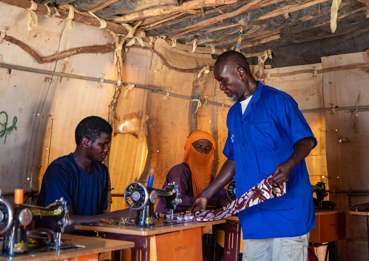 Niger. A refugee tailor instructs a trainee in his workshop
