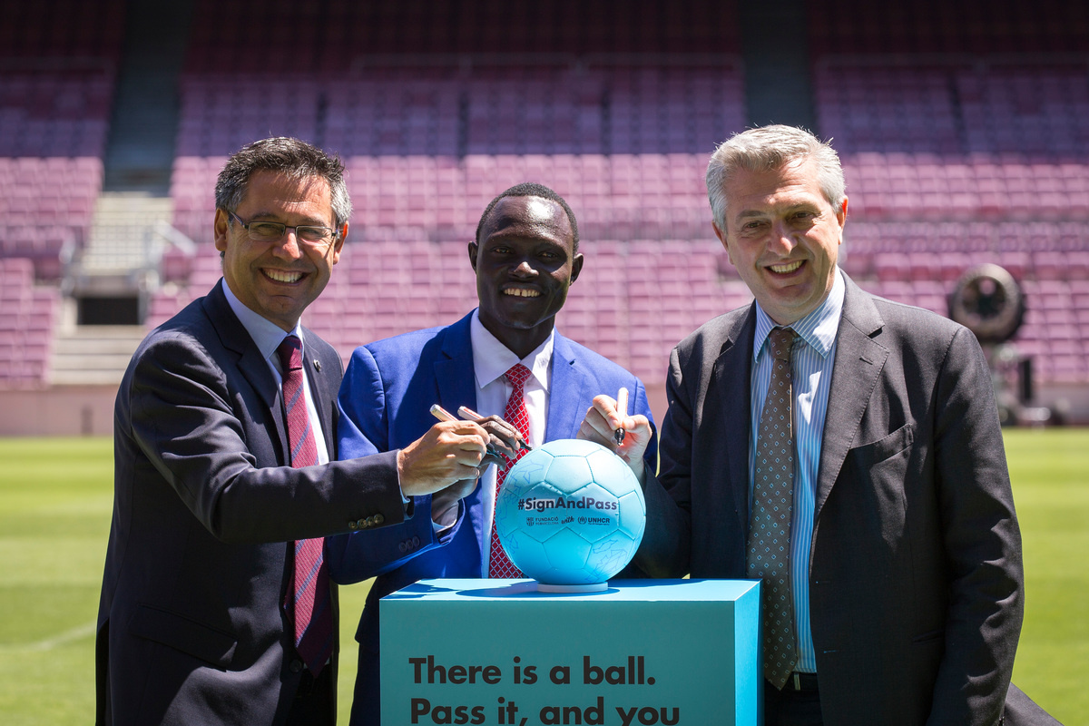 Spain. Josep Maria Bartomeu, Paulo Lokoro and Filippo Grandi sign off the ball of the #SignAndPass campaign in the Camp Nou footbal field.