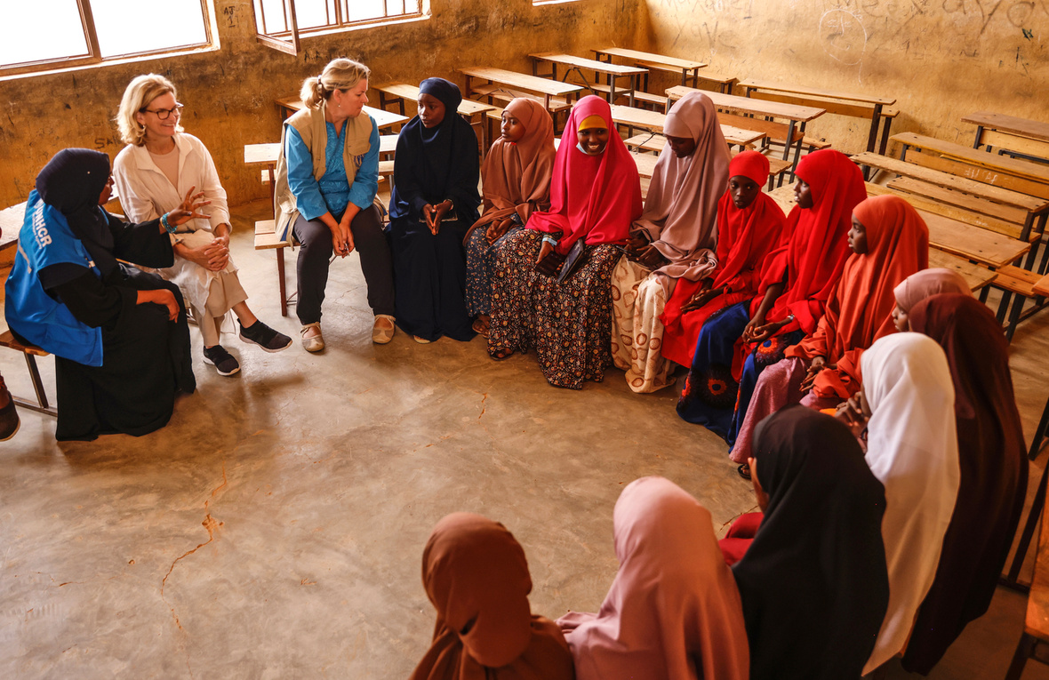 Refugee schoolgirls and staff from international organizations sit in a classroom. 