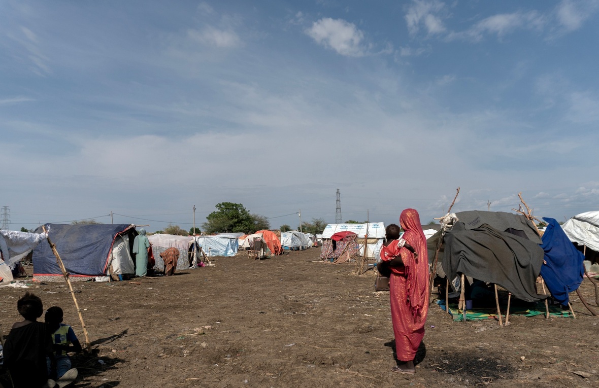 Fatima, displaced from her home in Kurmuk, holds her youngest child in the Al Karama gathering site in Damazine, Blue Nile State, Sudan.