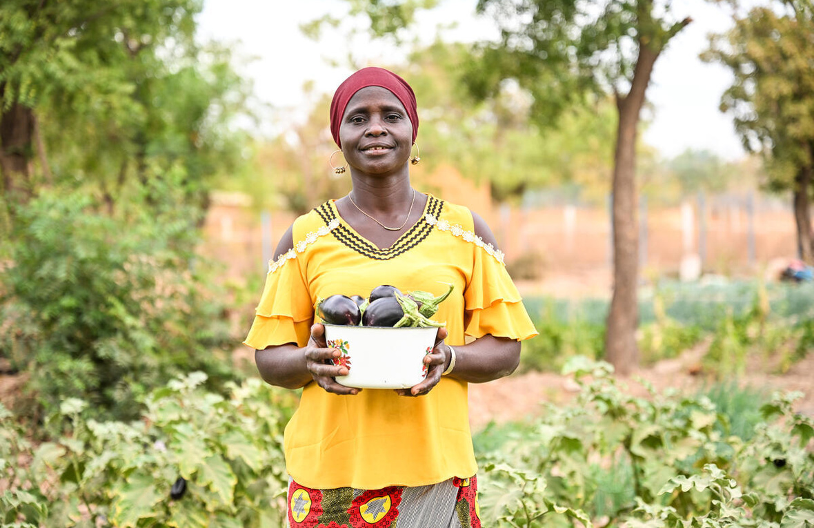 Burkina Faso. IDP Marie Dabini holding her eggplant harvest