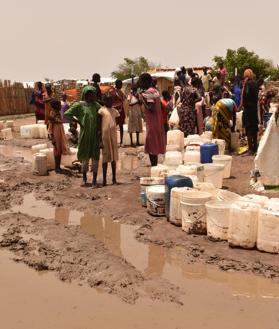 Women and children line up to fetch water from the tap stands in Um Sangour camp, White Nile State.