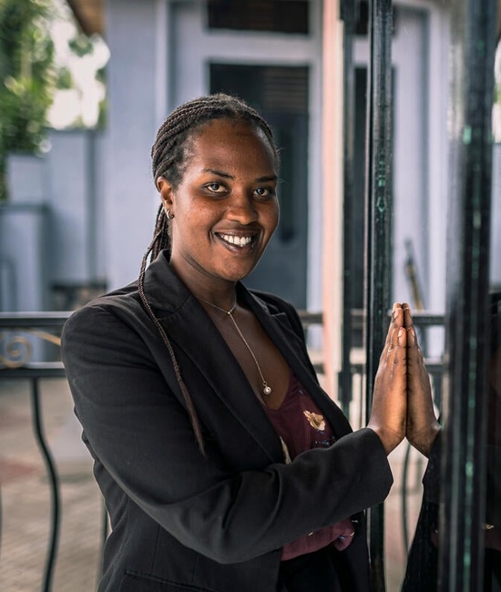 A woman smiles at the camera and holds her hand up against a reflection of herself.