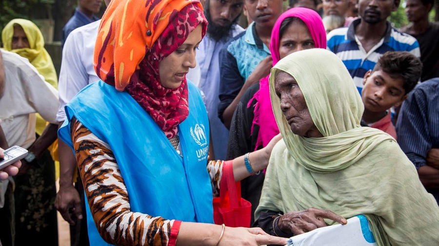 An elderly woman receives a tarpaulin from a UNHCR staff member, in Bangladesh.