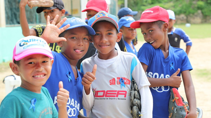 Four boys playing baseball and smiling at the camera