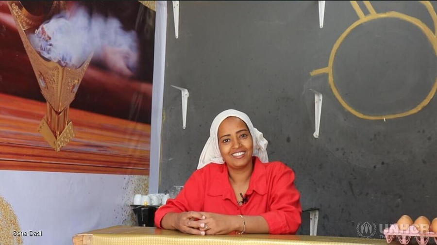 A woman wearing a bright red shirt stands behind the counter of a cafe