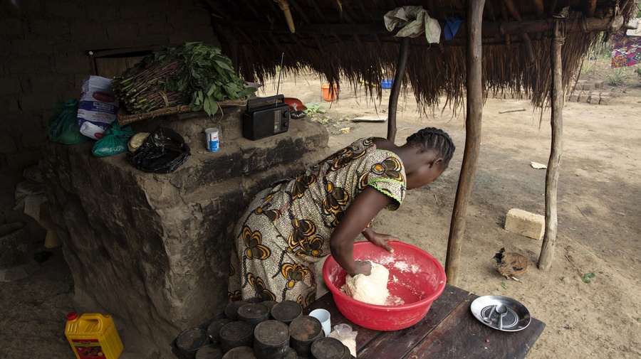 Rose kneads dough in front of an oven at the home of Sister Angélique Namaika in Dungu