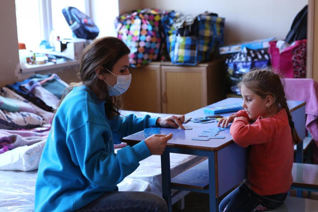 Caption: Lia, 5, plays dominoes with a UNICEF staff member in a shelter where she lives with her mother, sister and grandmother. Photo: © UNICEF Armenia/Galstyan
